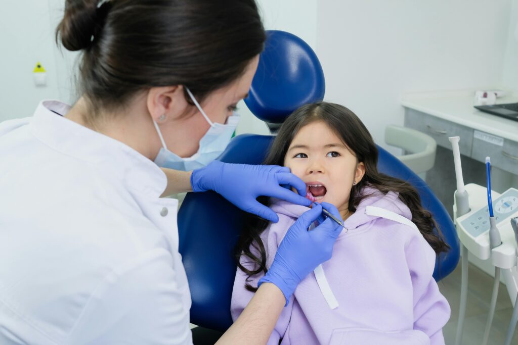 pexels-photo-7800568-7800568 Young girl receives dental checkup from a female dentist in a clinic.